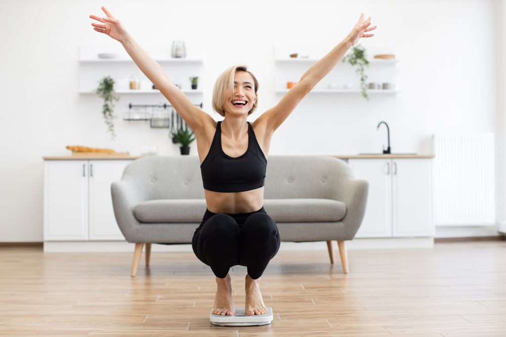 Happy woman celebrating weight loss on scale after Tirzepatide GLP-1 injections at Chicago Weight Loss Clinic